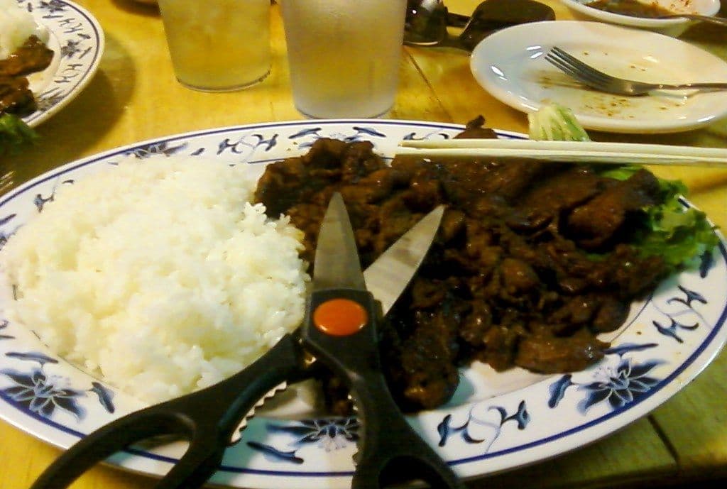 Kitchen scissors resting on a plate of Korean barbecue meat