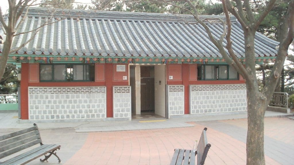 A free-standing public restroom building in a Korean park, built in traditional style